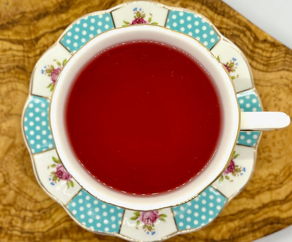 Herbal blood orange tea brewed to a bright pink color in a polk a dot tea cup
