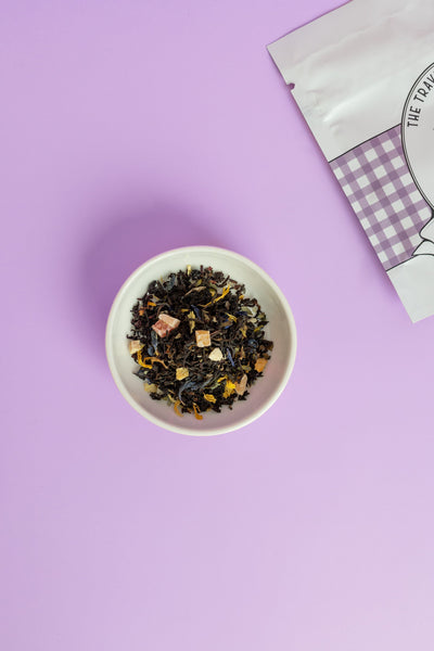 Lavender peach black tea loose leaves in a bowl with a purple background