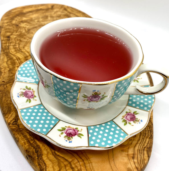 Caffeine free, herbal, loose leaf blood orange tea brewed to a bright pink color in a teacup